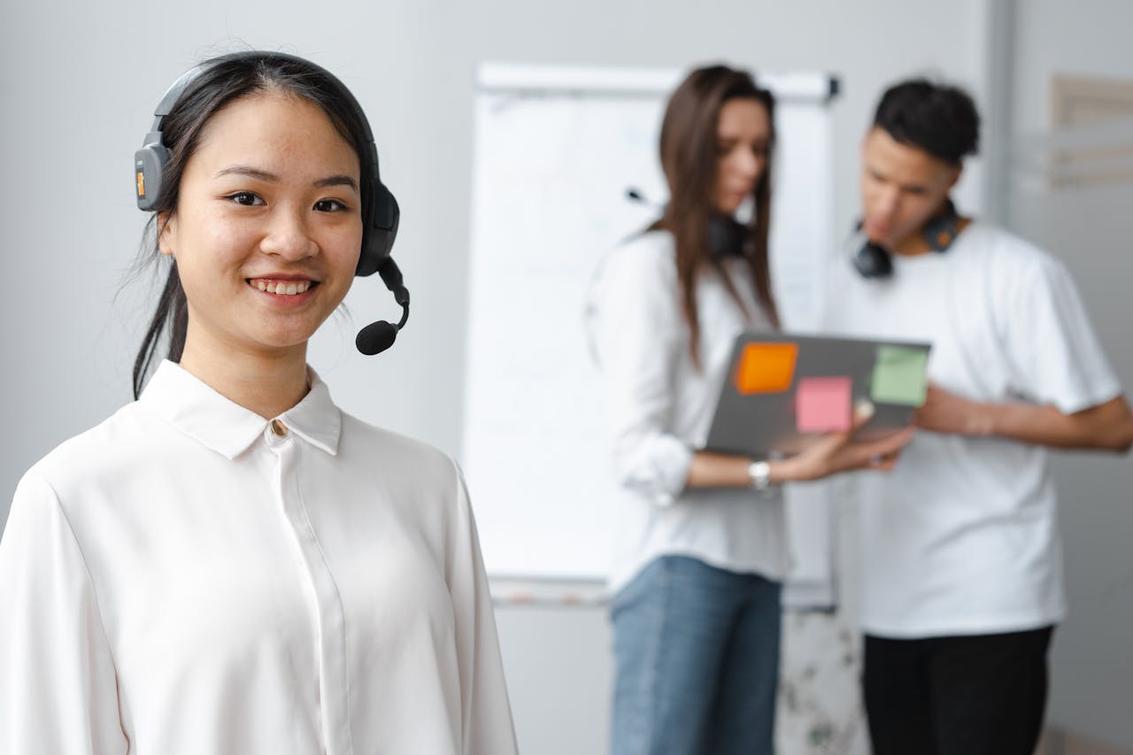 Friendly female call center agent with headset smiling in office setting.